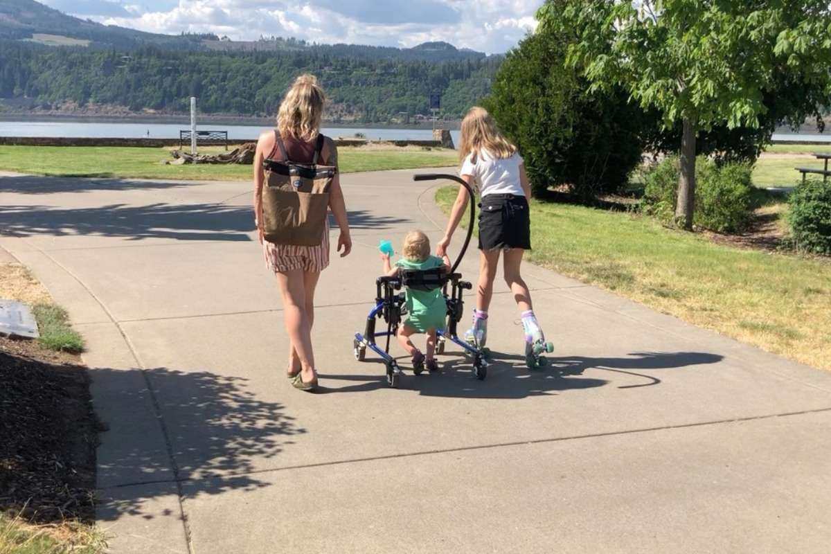 Woman walking with her daughters, one of them in a wheelchair