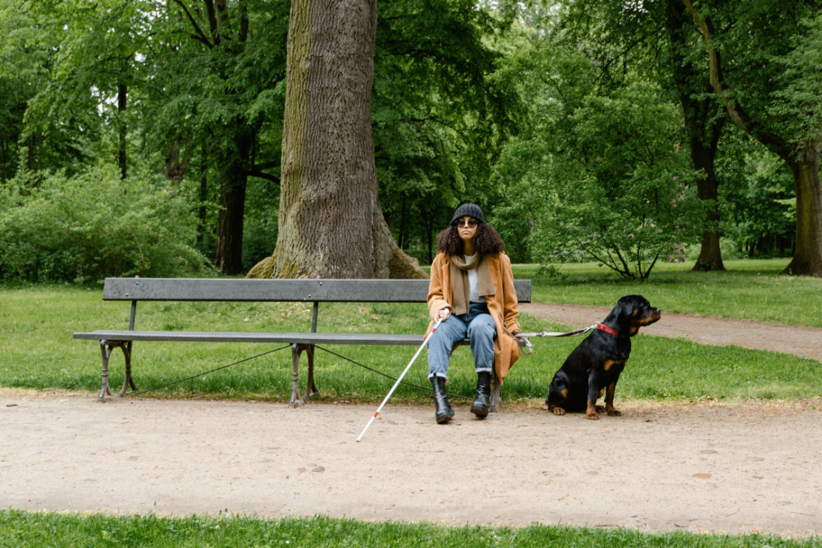 Blind woman sitting in park with dog