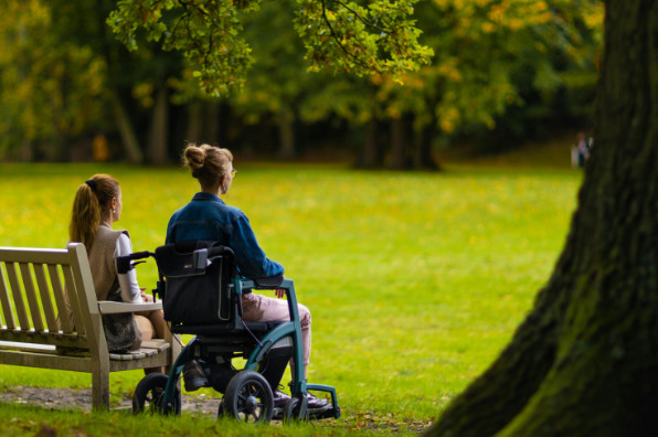 Two women sit in park, one woman in wheelchair